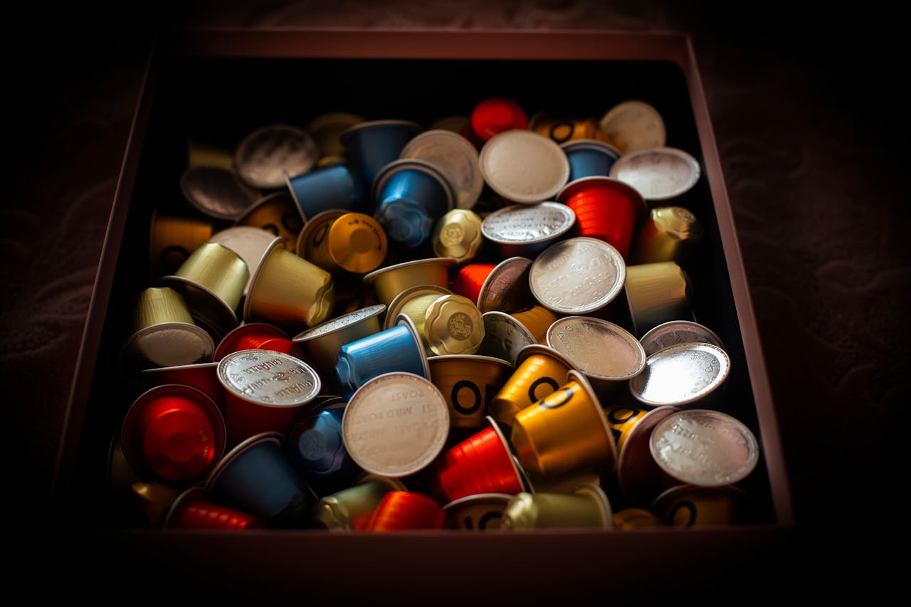 Vibrant collection of coffee capsules overflowing in a dark box, creating a colorful and rich visual.